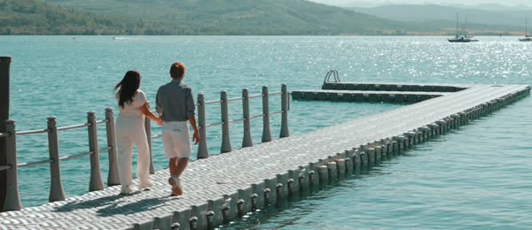 Couple walking hand in hand along a lakeside dock in a realtor branding video