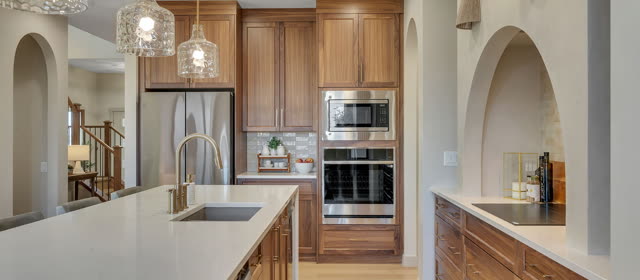 Kitchen with walnut cabinets, arched openings and a quartz island