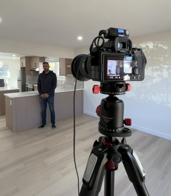 Camera on a tripod filming a realtor in a new Calgary kitchen on shoot day