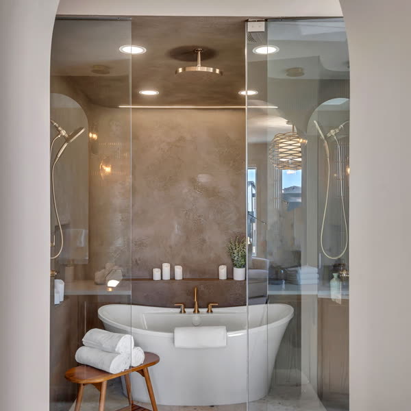 Arched entry to an ensuite with a freestanding tub and glass shower